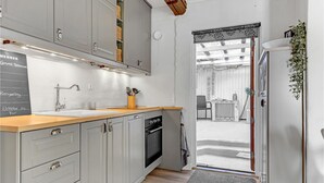 Eine moderne Küche mit grauen Schränken, einer Holz Arbeitsplatte und einem eingebauten Backofen.