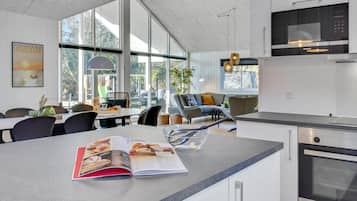 A modern kitchen with a large island, a dining area with a view, and a Siemens oven.