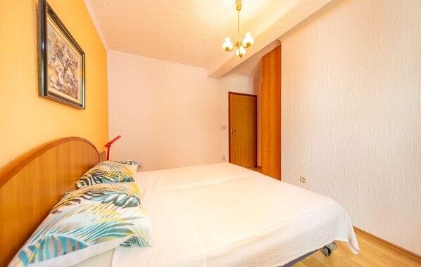 A bedroom with a bed, a wooden headboard, a ceiling light, and a door.