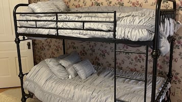 Un letto a castello con carta da parati a motivi floreali e una porta bianca.