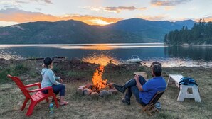 Two people sitting by a campfire overlooking a lake with mountains in the background. - Croll Cabins-Armstrong Library- #5 at Vallecito Lake, private lawn, great views! (Bayfield)