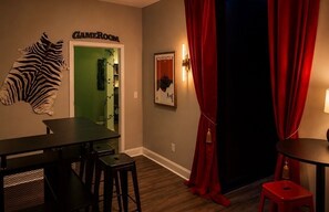 A room with a zebra head decoration, a table, chairs, a red curtain, and a door labeled 'GAMEROOM'.