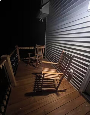 A wooden deck with two rocking chairs and a metal railing.