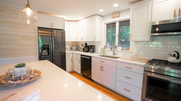 A modern kitchen with white cabinetry, stainless steel appliances, and a large island.