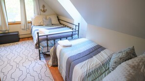 A bedroom with two beds, a patterned rug, and a window with curtains.