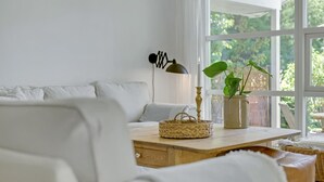A cozy living room with a white sofa, a wooden coffee table, a floor lamp, and a potted plant by a large window. - 4 bedroom lovely home in Gilleleje (Gilleleje)