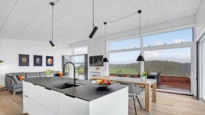 A modern kitchen with a central island, large windows offering a view of the outdoors, and a dining area with a view of the landscape. - 3 bedroom awesome home in Aabenraa (Aabenraa)