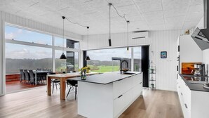 A modern kitchen with a large island, white cabinetry, and pendant lighting. - 3 bedroom awesome home in Aabenraa (Aabenraa)