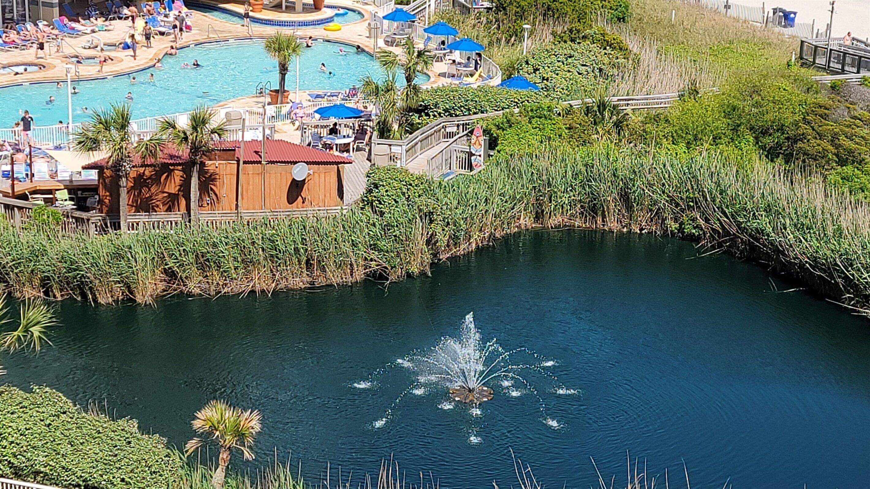 A resort with multiple swimming pools, a water fountain, and lush greenery.