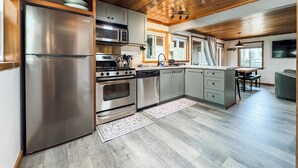 A modern kitchen with stainless steel appliances, wooden ceiling, and a dining area with a view. - Croll Cabins-Martin Lakeside (#2) at Vallecito Lake (Bayfield)
