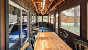 A wooden interior with a long table and chairs, large windows, and a view of the outside. - Croll Cabins-Martin Lakeside (#2) at Vallecito Lake (Bayfield)