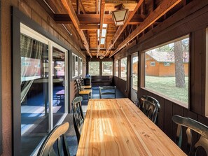 A wooden interior with a long table and chairs, large windows, and a view of the outside. - Croll Cabins-Martin Lakeside (#2) at Vallecito Lake (Bayfield)