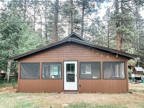 Une petite cabane en bois avec une porte, de grandes fenêtres et un toit en pente.