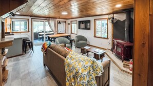 A cozy cabin interior with a wooden ceiling, a dining area, a sofa with a blanket, and a fireplace. - Croll Cabins-Martin Lakeside (#2) at Vallecito Lake (Bayfield)