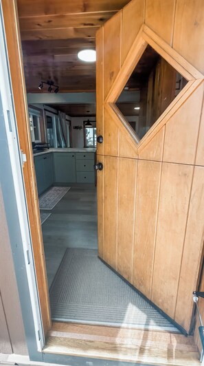 A wooden door with a diamond-shaped window, leading to a room with a kitchen area visible in the background. - Croll Cabins-Martin Lakeside (#2) at Vallecito Lake (Bayfield)