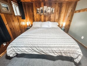 A bedroom with a large bed, wooden walls, and framed pictures. - Croll Cabins-Martin Lakeside (#2) at Vallecito Lake (Bayfield)