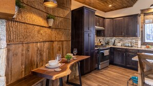 A rustic kitchen with dark wooden cabinets, a wooden bench, and a dining table set with plates and glasses. - Stillness Springs at Eagles Nest - Pet Friendly, Two master suites, firepit, hot tub, creek, 1 acre! (Banner Elk)