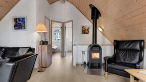 Un acogedor espacio tipo loft con chimenea, muebles de cuero y obras de arte en las paredes.