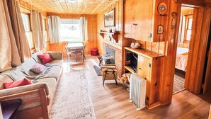L’intérieur chaleureux d’un chalet avec un plancher en bois, un canapé, une table à manger et une cheminée.
