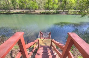 A wooden staircase leading to a dock over a calm body of water surrounded by trees.
