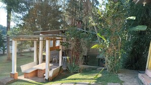 Un espace extérieur abrité, doté d’une structure en briques, entouré de verdure et d’arbres.