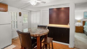 A modern kitchen with a round marble table, dark cabinets, and a ceiling fan.