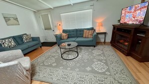 A living room with a sofa, armchair, coffee table, and TV.