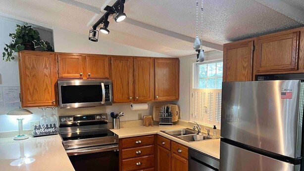 A modern kitchen with wooden cabinets, stainless steel appliances, and a central island.