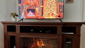 A fireplace with a TV above it displaying a Christmas scene.