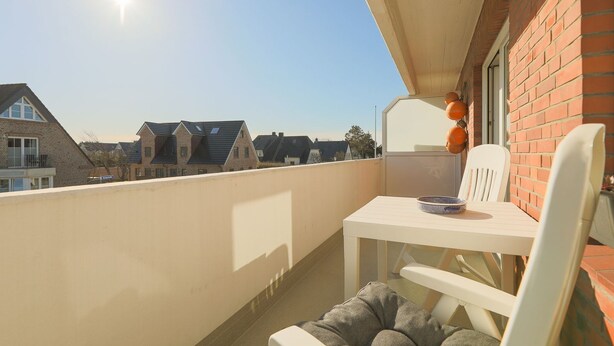 A balcony with a table and chairs, a view of neighboring houses, and a clear sky. - Friesennerz - Hedighuis - Friesennerz (Sylt)