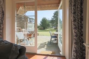 Una habitación con puerta corrediza de vidrio que da a un patio exterior con mesa y sillas.