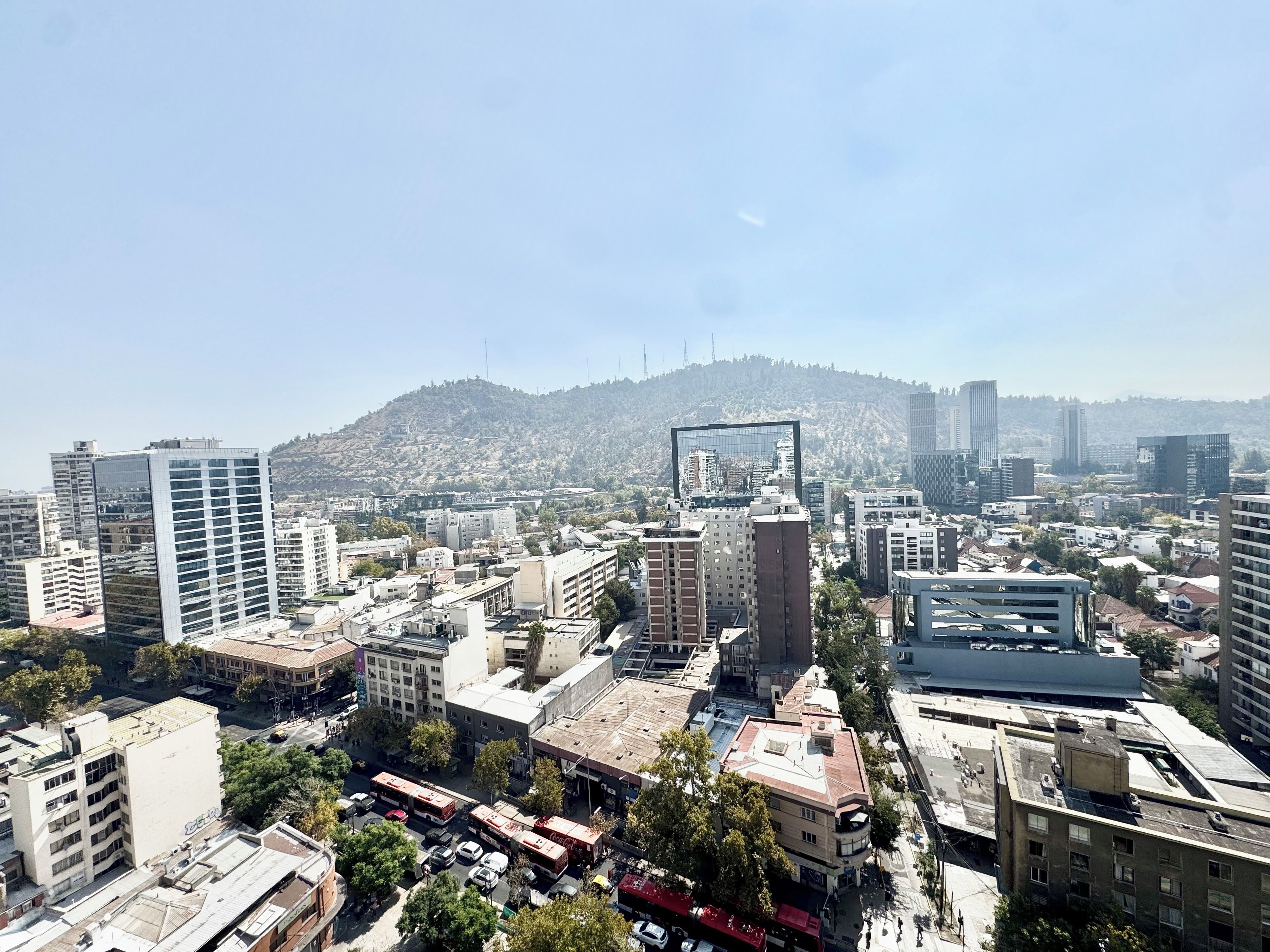 A cityscape with various buildings, including high-rise structures and a central building with a distinctive glass facade.