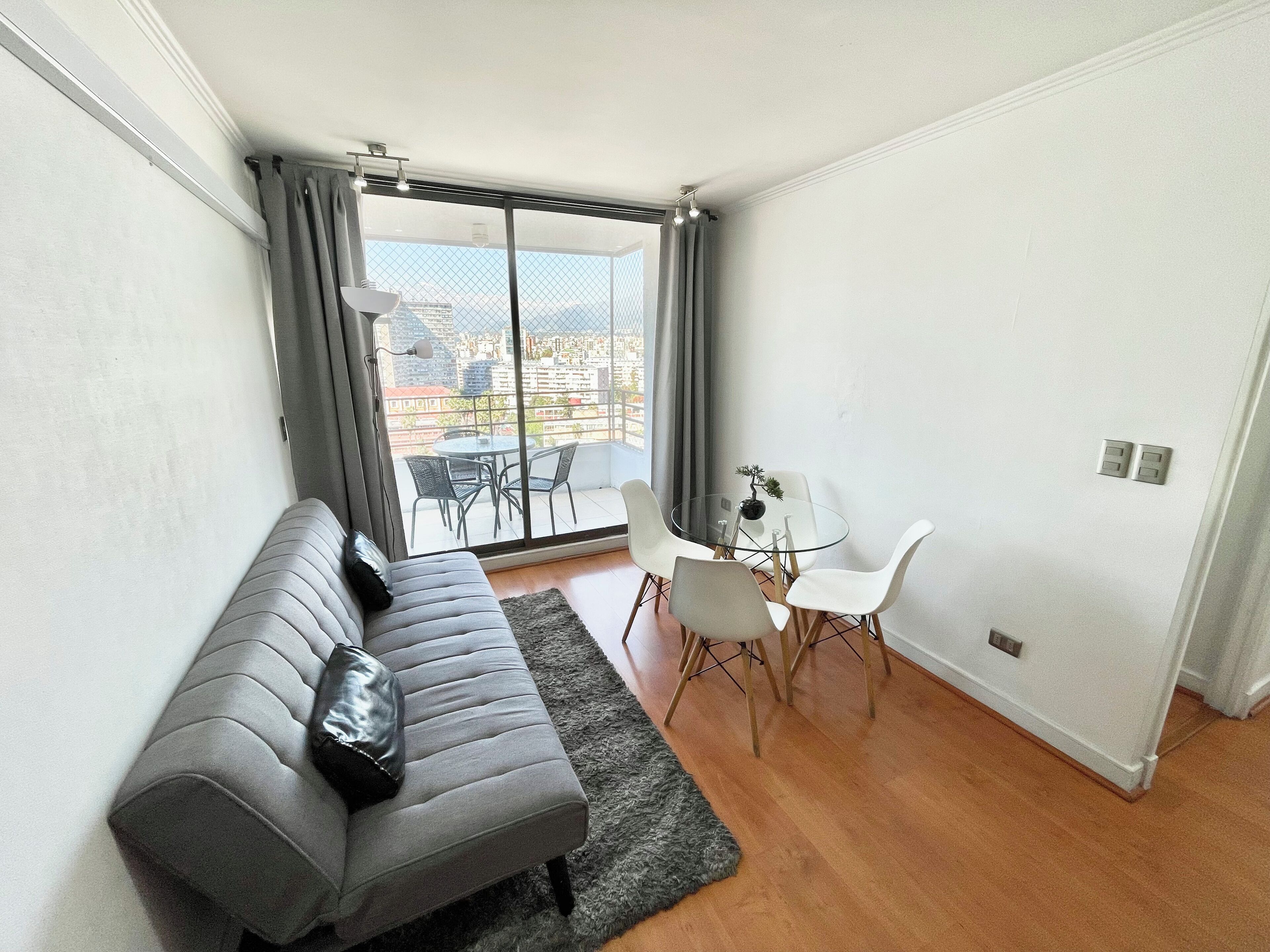 A modern living room with a grey sofa, a small round table, and two white chairs.