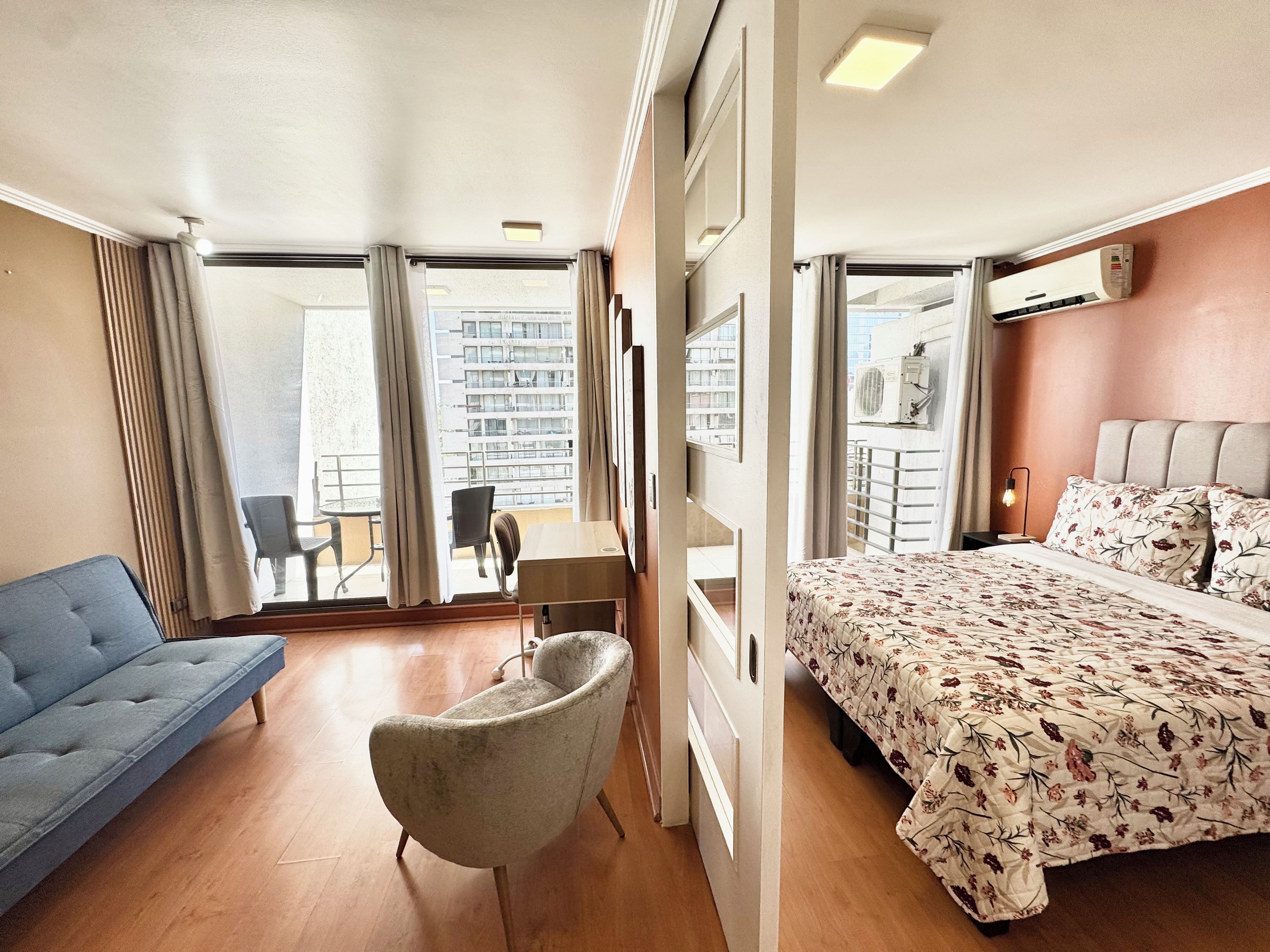 Habitación de hotel con cama, sofá, sillón, escritorio y vistas al exterior.