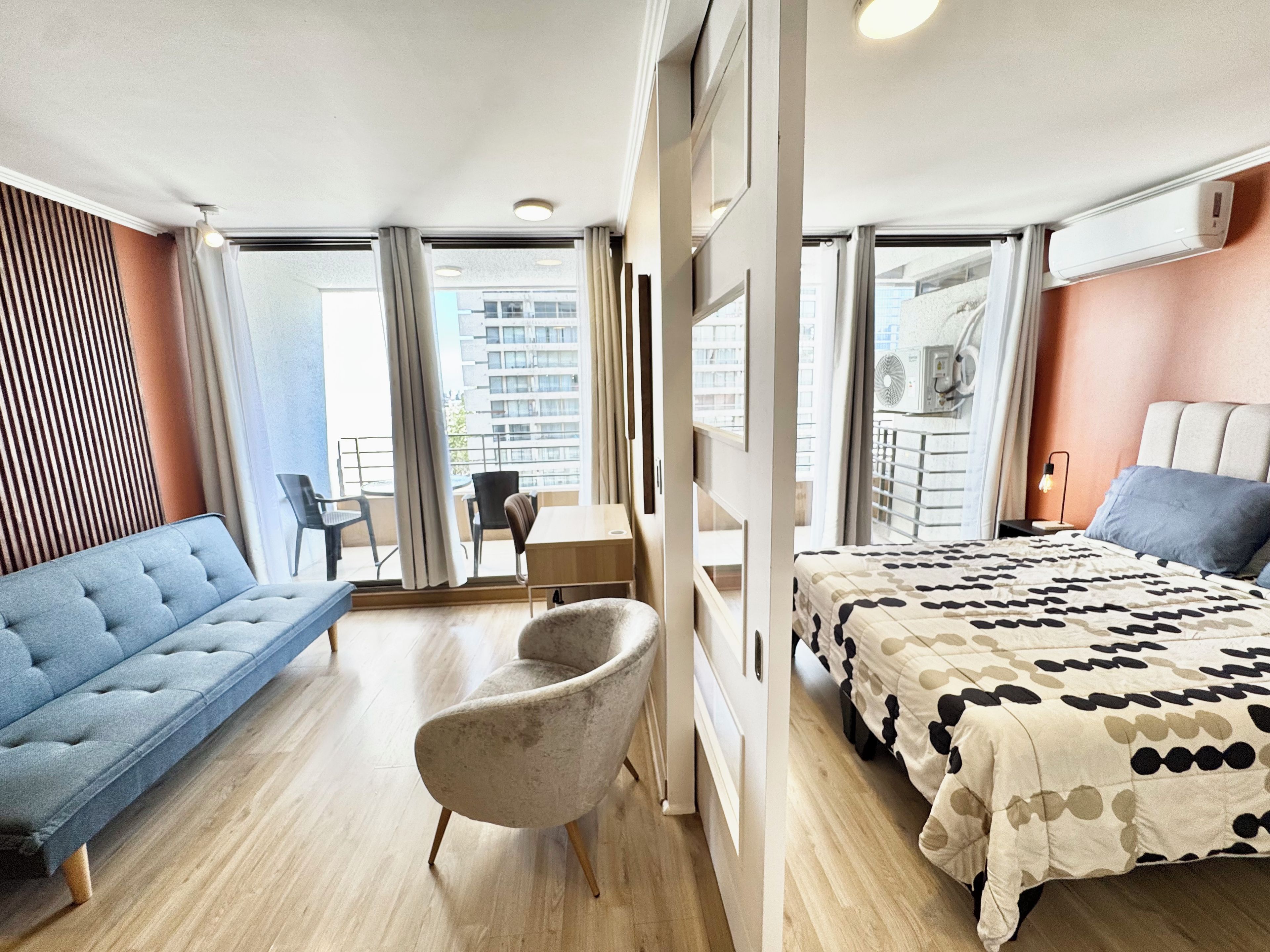 Una habitación de hotel moderna con cama, sofá, sillón, escritorio y vistas a la ciudad.