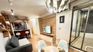 Una sala moderna con un sofá, una mesa de vidrio para comer y un televisor.