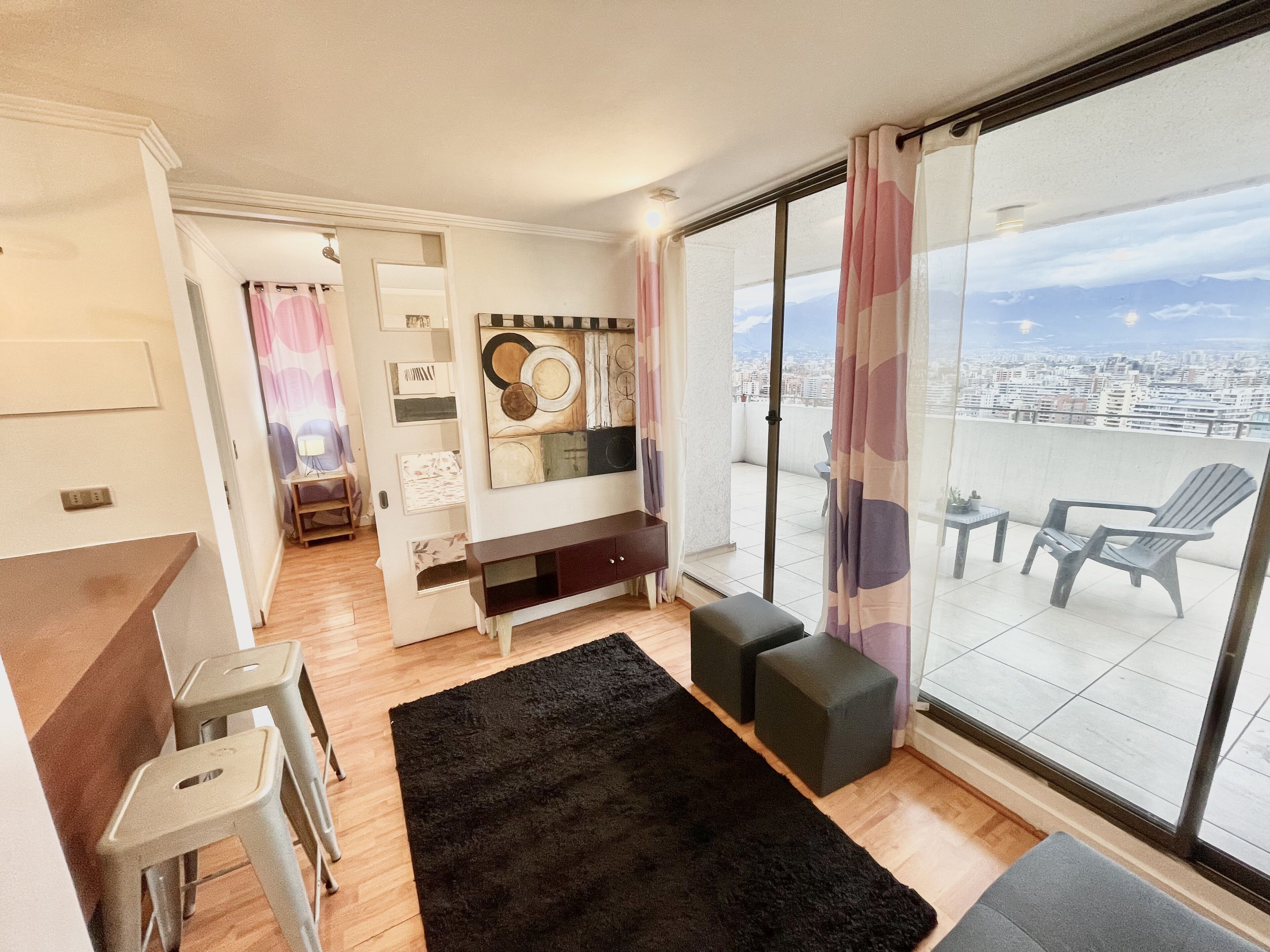 A modern living room with a large sliding glass door leading to a balcony with a city view.