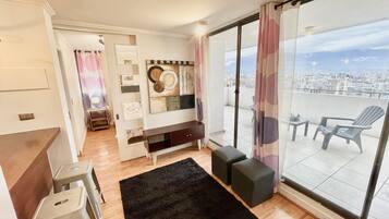 A modern living room with a large sliding glass door leading to a balcony with a city view.