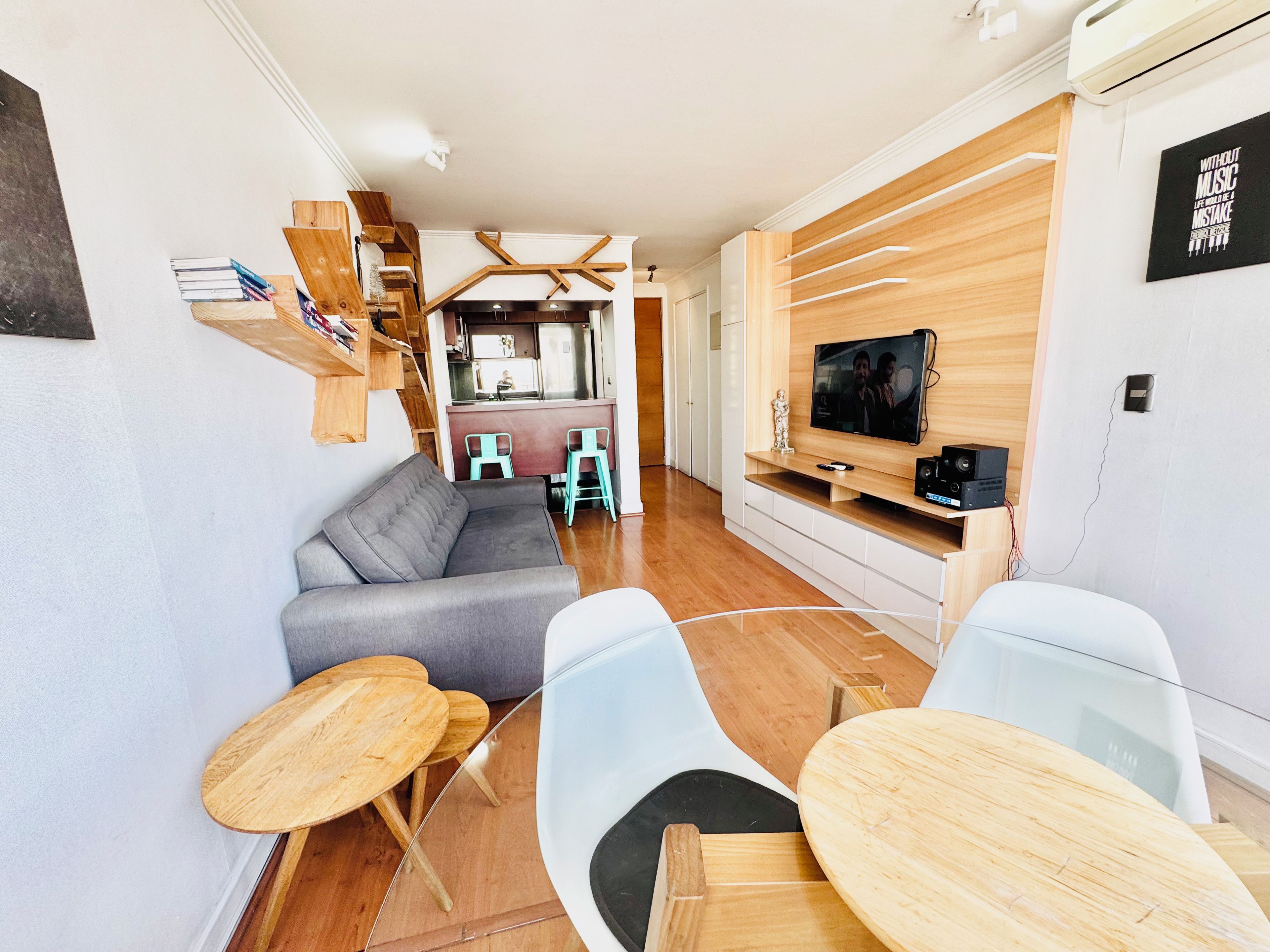 A modern living room with a grey sofa, wooden coffee table, and a TV on a wooden stand.