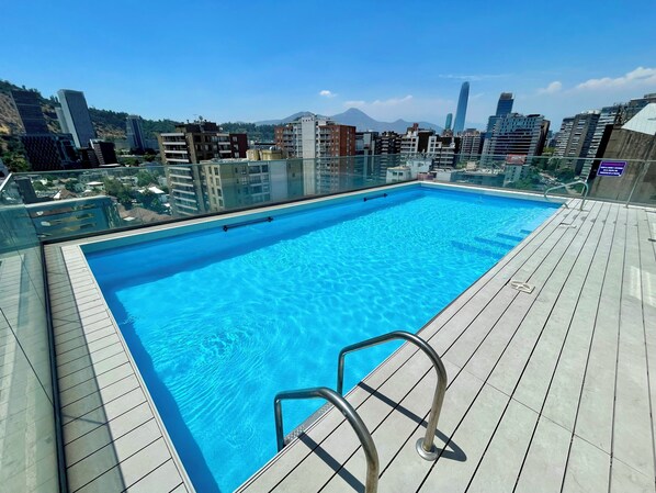 A rooftop swimming pool with a clear view of surrounding buildings and a mountain in the background. - Rho.cl (Santiago)