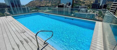 A rooftop pool with a clear view of surrounding buildings and a hilly landscape.