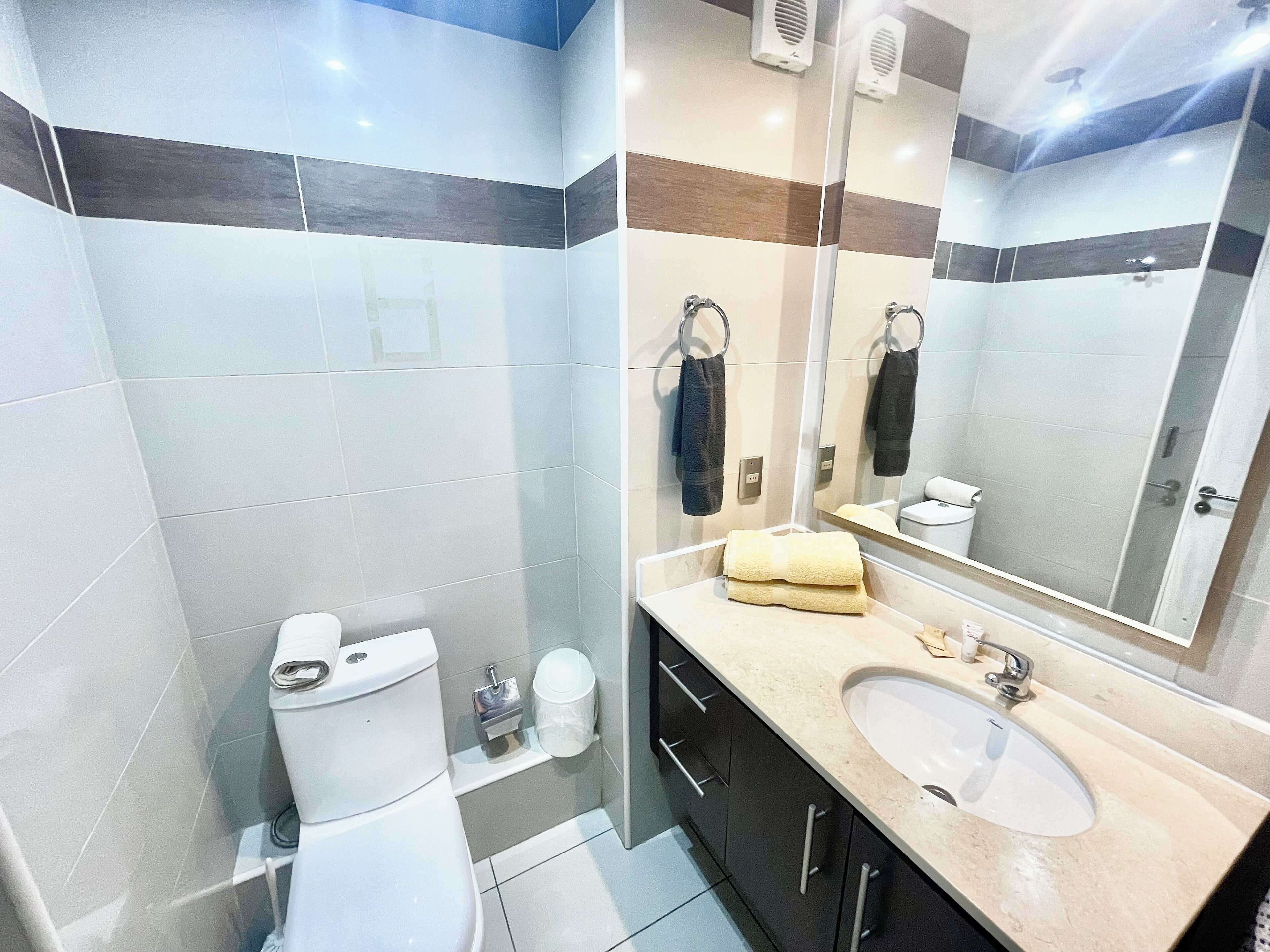 Un baño moderno con inodoro, lavabo y espejo.