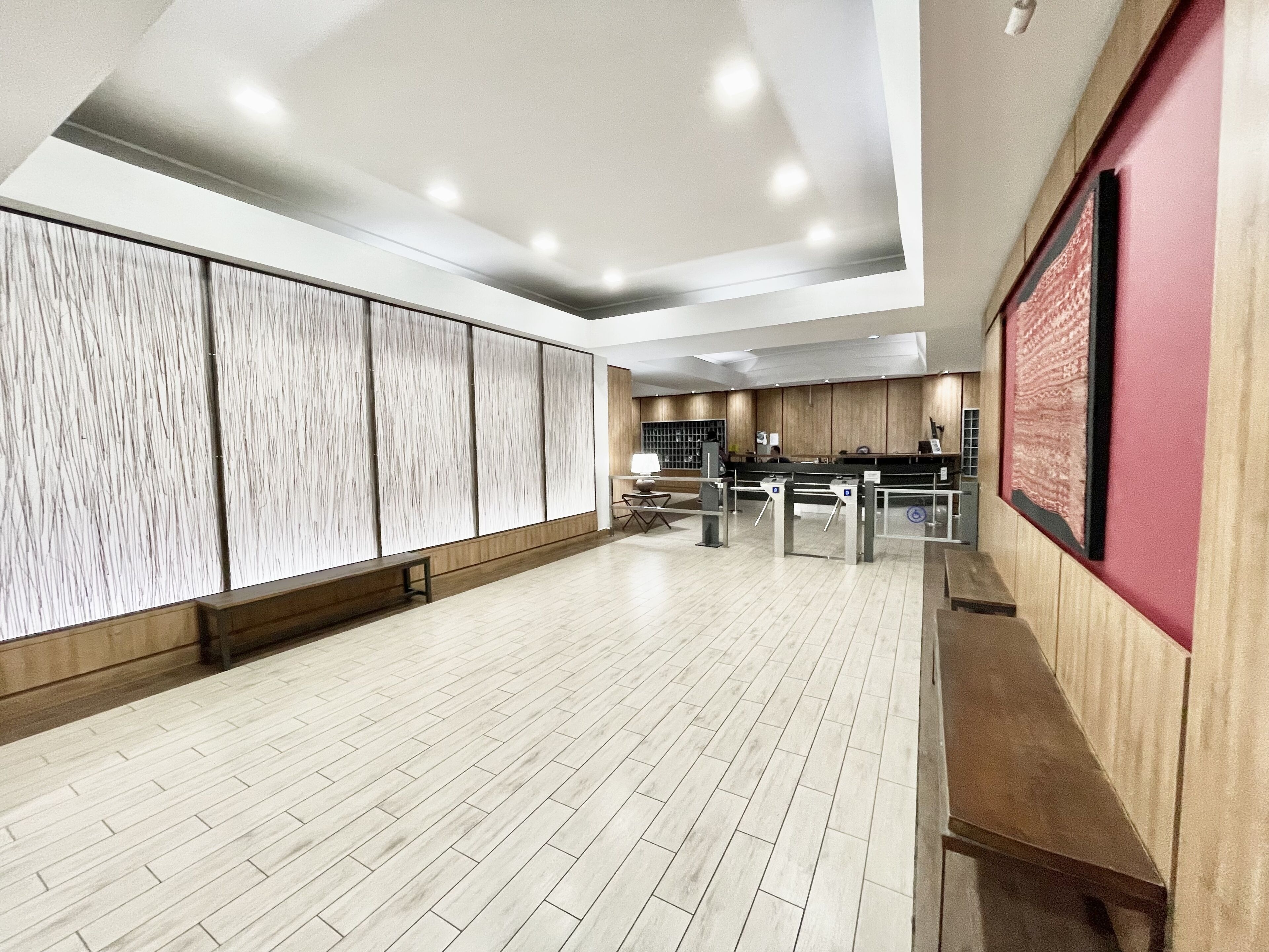 Un vestíbulo amplio con piso de madera, un mostrador de recepción y un diseño de techo moderno.