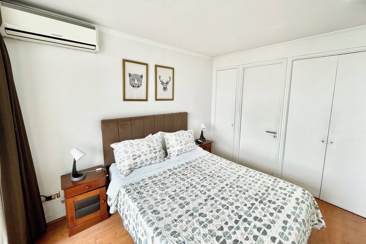 A bedroom with a bed, nightstands, a lamp, a wardrobe, and two framed pictures on the wall.