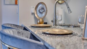 Une cuisine dotée d’un plan de travail en marbre, d’un évier de couleur dorée et d’un verre à vin en verre.