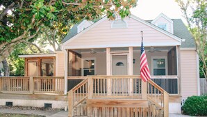 Ein zweistöckiges Haus mit Veranda, einer Holzterrasse und einer amerikanischen Flagge.