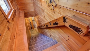 Un interior de madera con una escalera que baja a un nivel inferior.