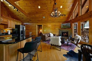 A log cabin interior with a kitchen, dining area, and living room.