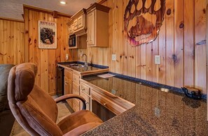 Una cocina con armarios de madera, encimera de granito y un reloj en la pared.