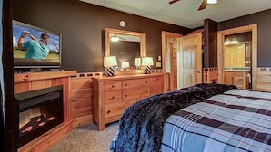 Un dormitorio con cama, cómoda, televisor y chimenea.